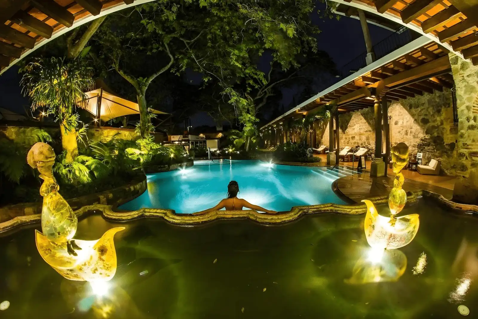 Casa Santo Domingo – Lujo Colonial y Bienestar en Antigua Guatemala Piscina exterior del hotel spa Casa Santo Domingo en Antigua Guatemala rodeada de vegetación y arquitectura colonial.